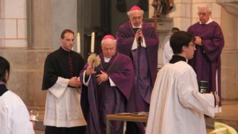 Bischof Dr. Konrad Zdarsa segnet die Asche mit Weihwasser.