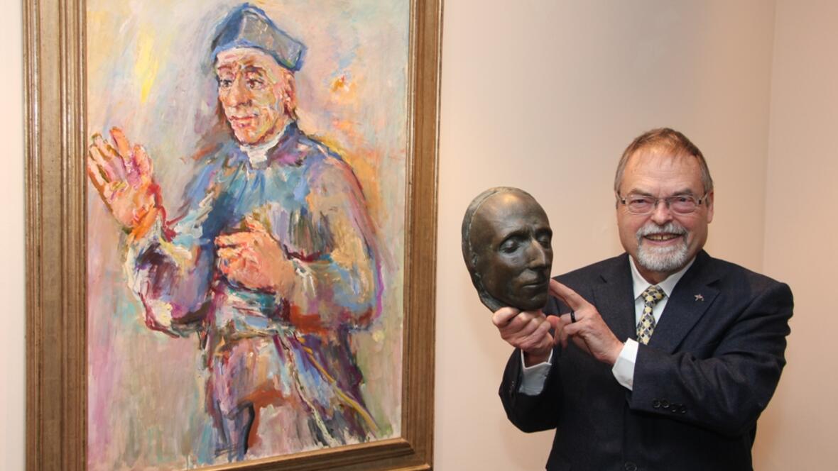 P. Peter Hinsen SAC hält die Totenmaske von Vinzenz Pallotti, die der Bildhauer Max Faller angefertigt hat, vor dem Bild Kokoschkas