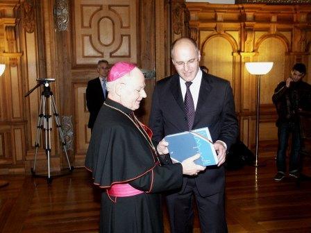 Oberbürgermeister Kurt Gribl überreicht Bischof Konrad Zdarsa ein Augsburger Stadtlexikon.
