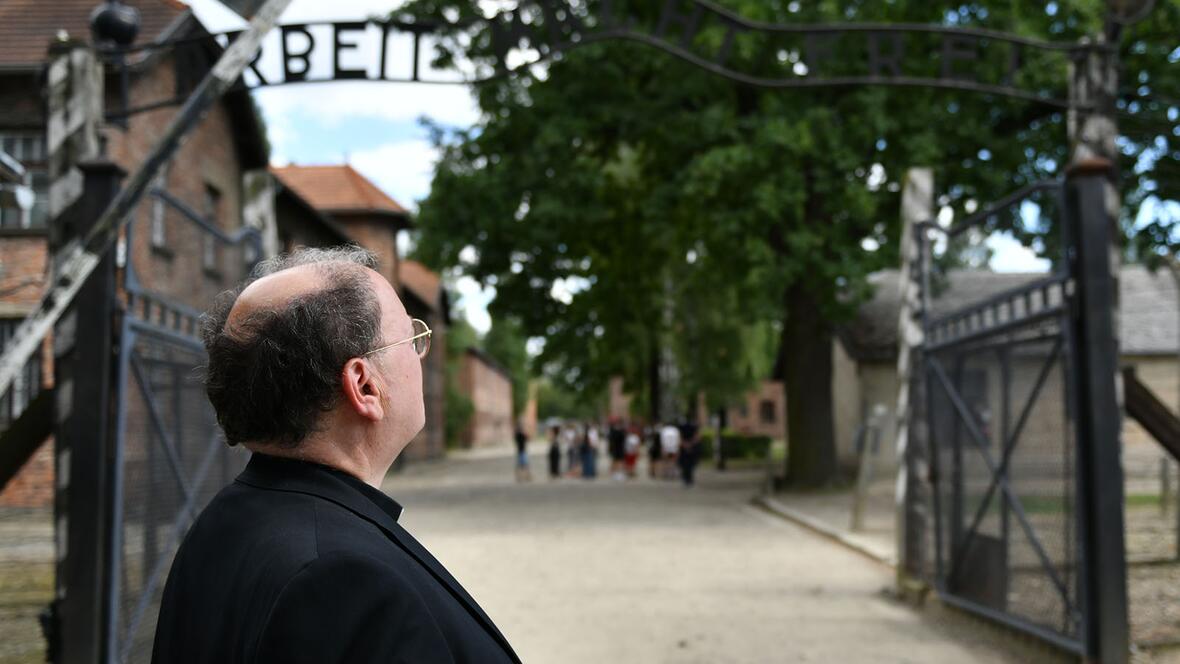 Bischof Bertram vor dem Eingangsbereich des Stammlagers Auschwitz mit dem berüchtigten Spruchband "Arbeit macht frei" (Fotos: Julian Schmidt / pba)