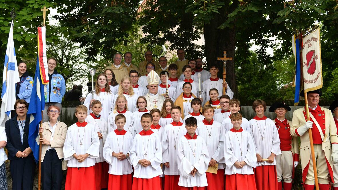 Ein Gruppenfoto mit den Fahnenabordnungen der unterschiedlichen Vereine, den Ministrantinnen und Ministranten sowie den Zelebranten am Eingang zur Ulrichskirche. 