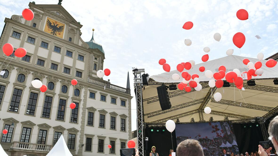 Rot und weiß färbte sich der Himmel über dem Augsburger Rathausplatz beim Auftaktfest für das Ulrichsjubiläum. Die Luftballone waren mit Bitten an den Bistums- und Stadtpatron versehen. (Foto: Maria Rösch / pba)  