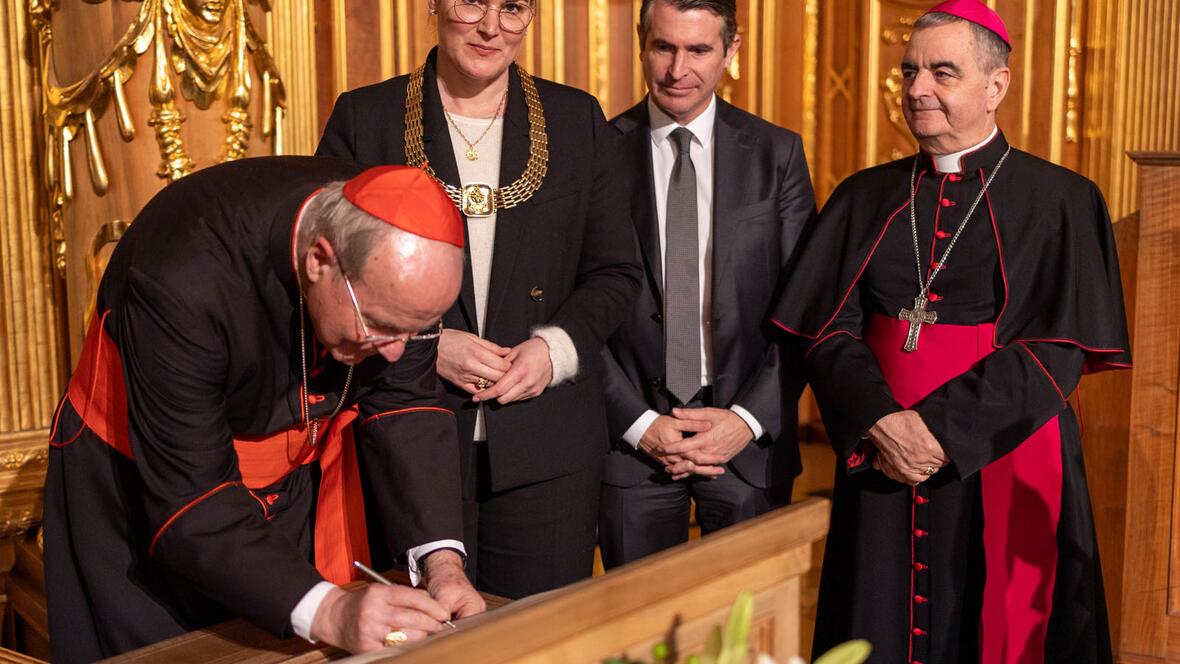 Kardinal Christoph Schönborn trägt sich ins Goldene Buch der Stadt Augsburg ein. (Foto: Julian Schmidt /pba)